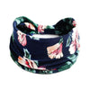 Un bandeau ou foulard pour les cheveux en tissu bleu foncé avec un imprimé floral bohème en tons rose et vert.