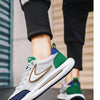 A close-up of a pair of white and green mesh running shoes with brown accents worn by a person.