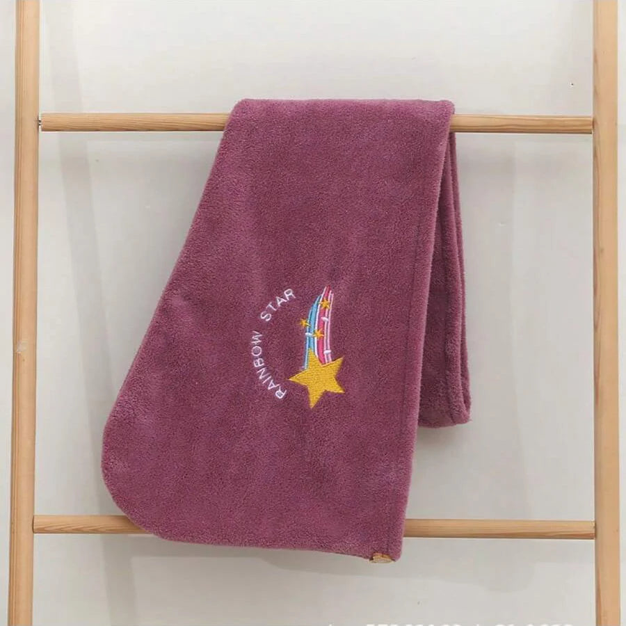 Tiefviolettes besticktes Handtuch hängt an einem Holzrack.