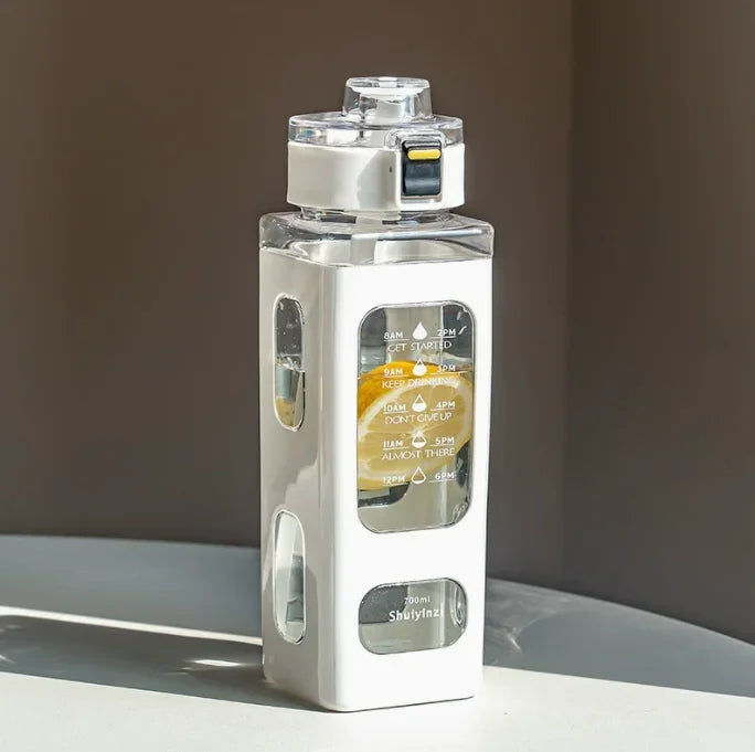 Klare, tragbare Sportflasche mit weißem Verschluss und Strohhalm auf einer hellen Oberfläche.