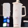 A white insulated thermos mug decorated with pink ribbon motifs and pearl inlay, shown next to a matching lid.