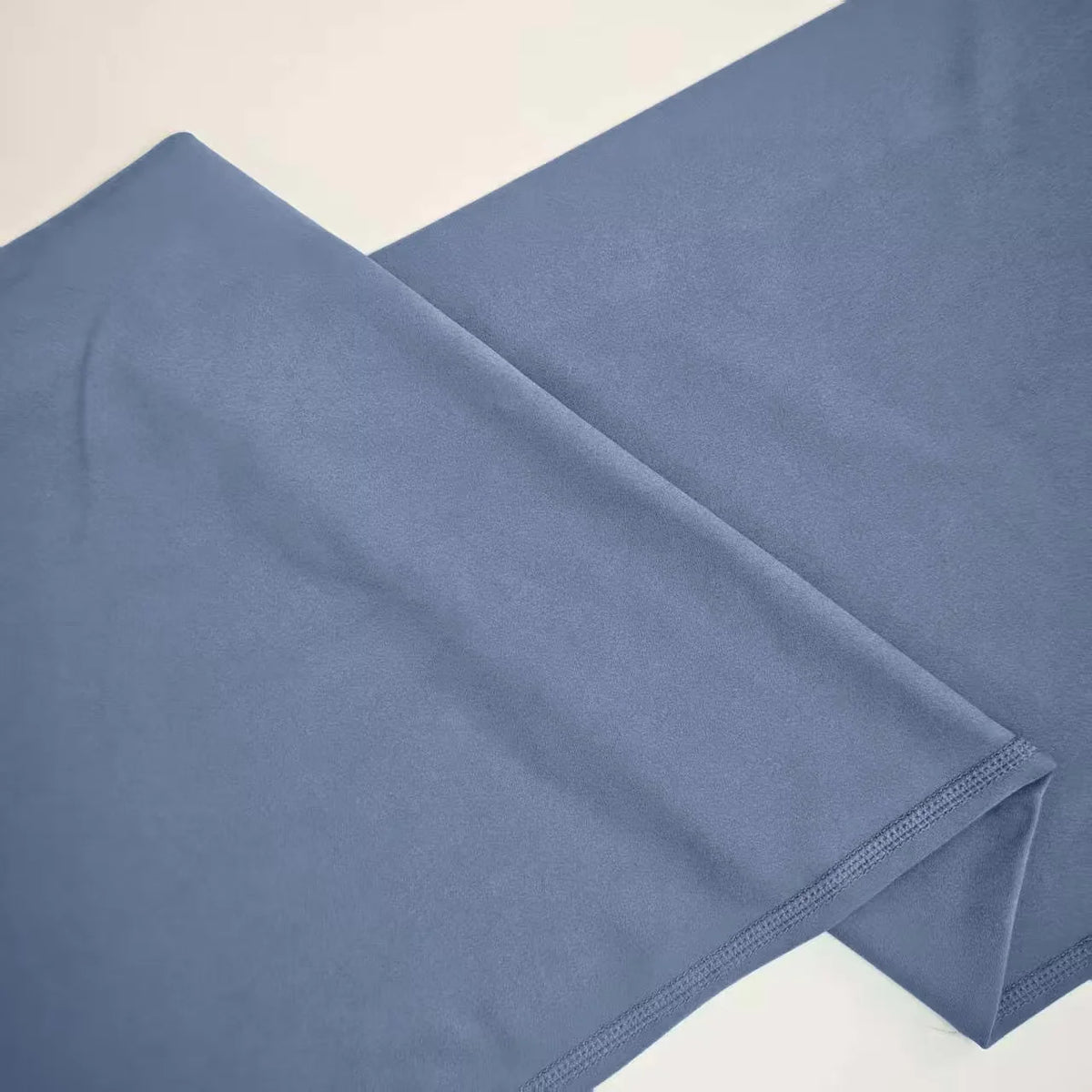 A close-up of a pair of soft blue NCLAGEN Straight Leg Yoga Pants folded and laid flat.