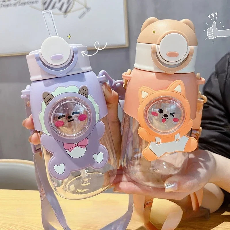 A hand holds a clear water bottle with a purple and pink cartoon animal design, featuring a bear face.