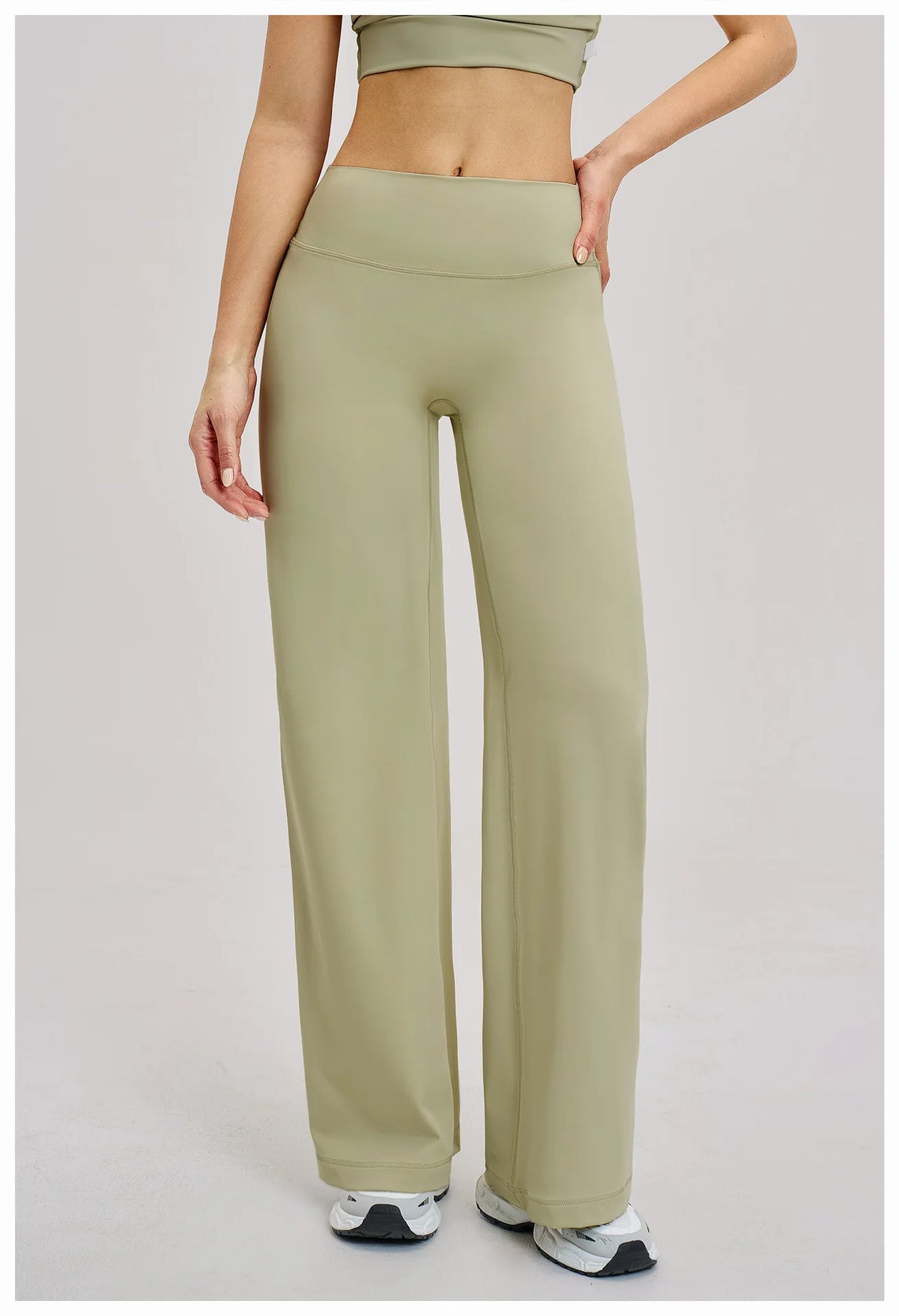 A woman wearing olive green high-waist flared yoga pants and a matching crop top.