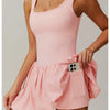Model trägt ein pinkes Performance-Tenniskleid mit Rundhalsausschnitt und plissierter Rock.