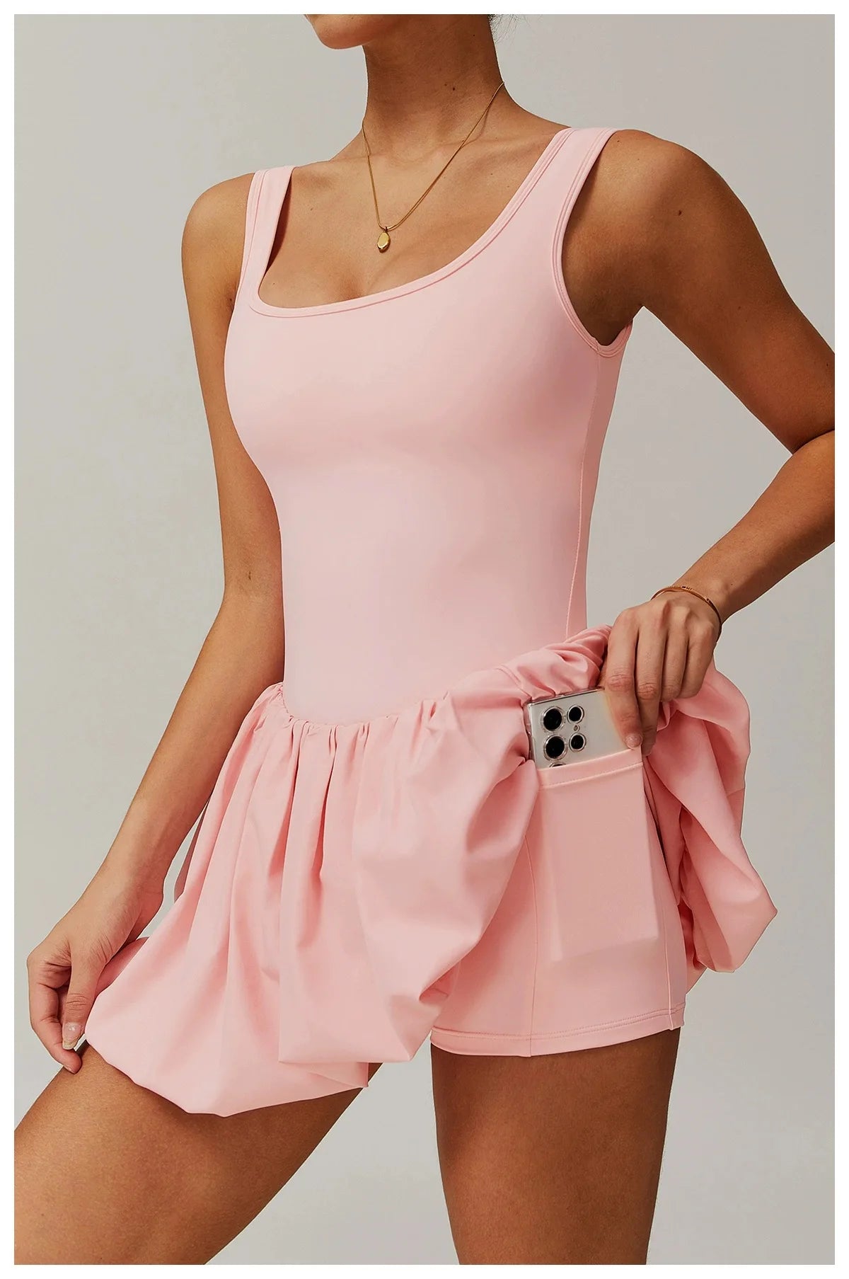 Model trägt ein pinkes Performance-Tenniskleid mit Rundhalsausschnitt und plissierter Rock.