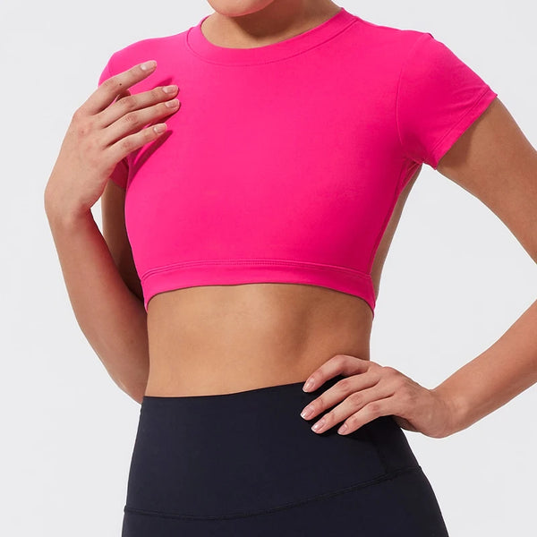 Una mujer vistiendo un top corto rosa brillante para fitness o yoga.