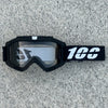 Black heavy-duty motorcycle and ATV goggles with a white strap resting on a gray surface.