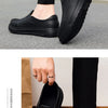 A close-up of a person wearing black men's anti-slip oil-resistant kitchen clogs.