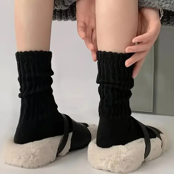 Une paire de chaussettes en tricot noir avec une bordure de fourrure synthétique blanche et des sangles noires montrées sur u