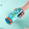 A hand holds a clear blue dinosaur silicone straw water bottle filled with liquid against a light teal background.