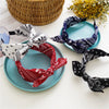 A collection of paisley bandana fabric headbands in white, red, and navy blue laid out on a light surface.