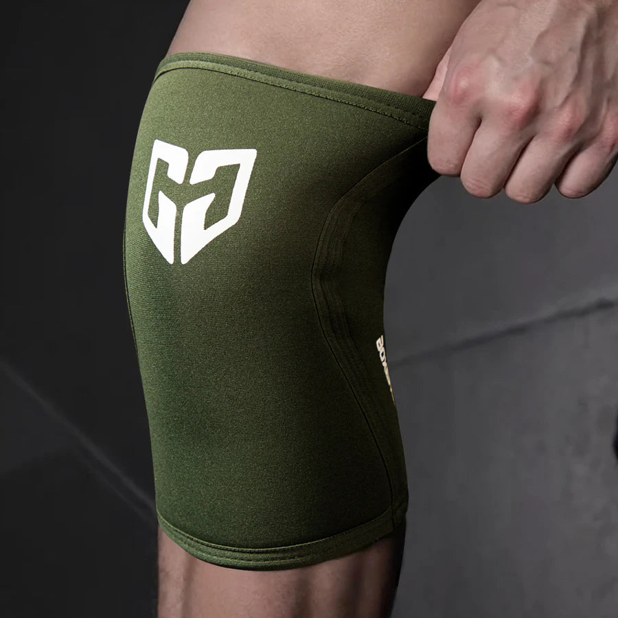 Olive green compression knee sleeve with a white geometric logo on a person's leg.