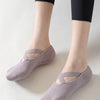 A pair of mauve non-slip yoga and gym socks with silicone grip worn on a person's feet.