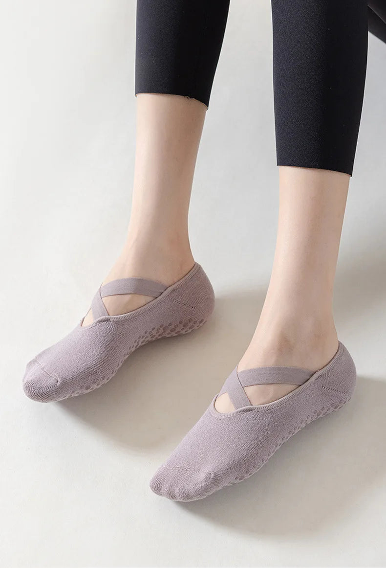 A pair of mauve non-slip yoga and gym socks with silicone grip worn on a person's feet.