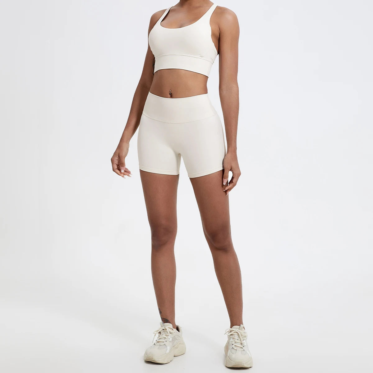Un modèle portant un haut de yoga beige à taille haute et un short assorti, dans un studio.