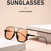 A pair of orange-tinted sunglasses with black frames resting on a white surface.