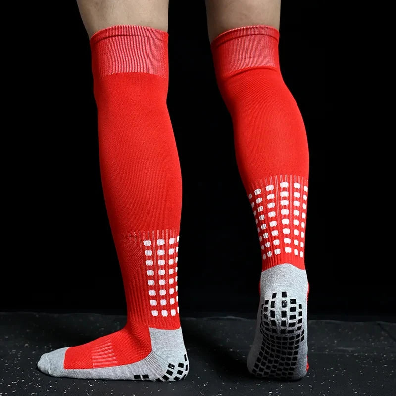 A pair of red and white long football training socks worn on a leg.