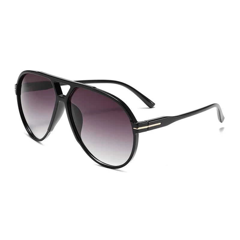 Eine schwarze Pilotenbrille mit Verlaufslinse und goldenen Akzenten.