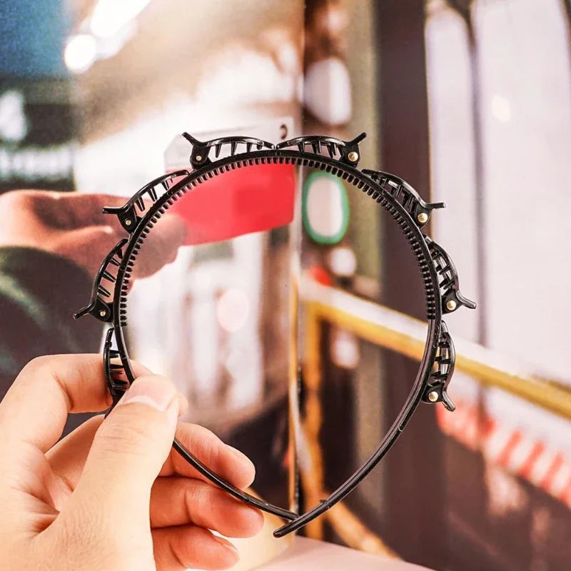 Una mano sostiene un set de clips y diadema para flequillo doble color negro contra un fondo desenfocado.