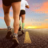 A person is running on asphalt with a yellow lane marker, wearing green calf compression sleeves.