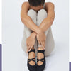 A person wearing black crisscross strap yoga socks is shown from the back.