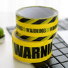 A roll of yellow and black industrial safety warning tape on a dark surface.