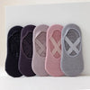 Una fila de cinco calcetines de yoga y pilates ajustados en tonos morado, rosa y gris.
