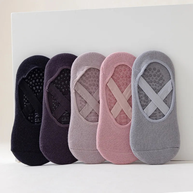 Una fila de cinco calcetines de yoga y pilates ajustados en tonos morado, rosa y gris.