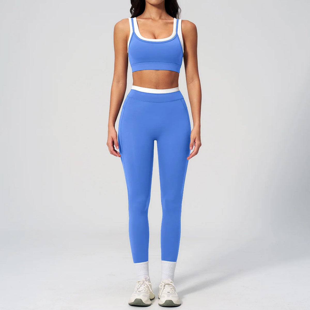 Eine Frau trägt ein blaues Yoga- und Trainingsanzug-Set mit क्रॉप탑 und langen Leggings.