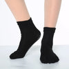 A pair of black rainbow yoga socks worn on a person's feet.