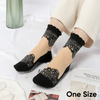 A pair of black sheer invisible lace socks worn on a foot, paired with cream-colored pants.