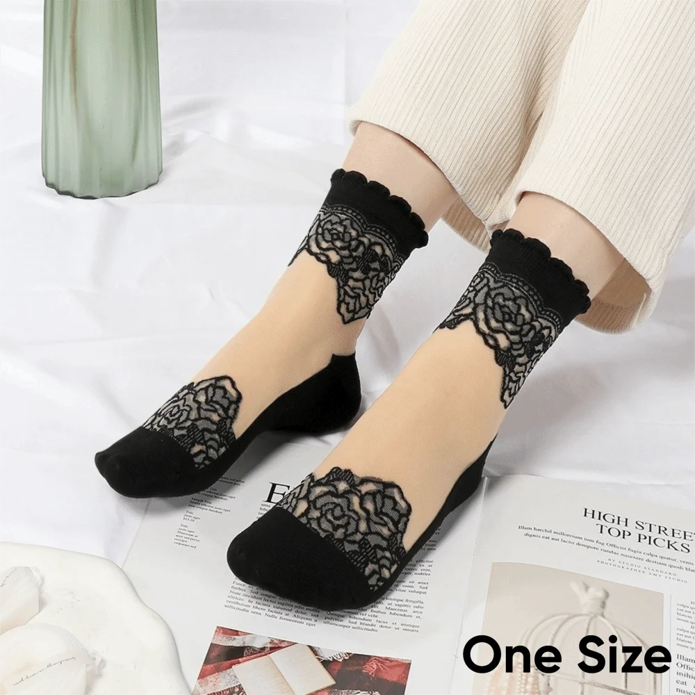 A pair of black sheer invisible lace socks worn on a foot, paired with cream-colored pants.