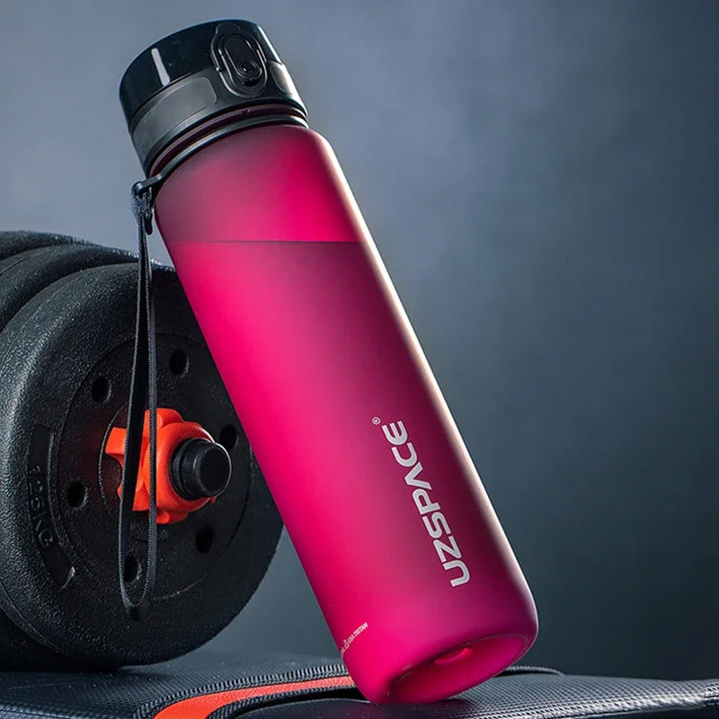 Pink USSPACE wiederverwendbare Sportflasche mit Trageleine neben einem schwarzen Trainingsrad