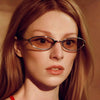Close-up portrait of a woman wearing retro oval sunglasses with a thin metal frame.