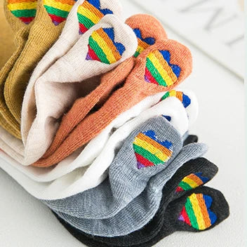 A stack of ten embroidered ankle socks in various colors including yellow, beige, orange, white, and gray.