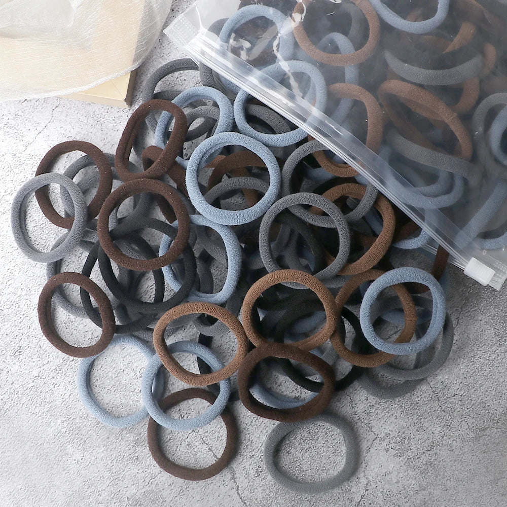 A pile of 50 pieces of mixed color elastic hair bands in various shades of brown and gray.