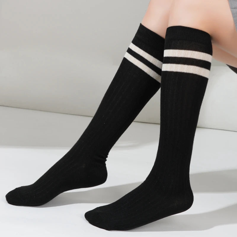 Black and white striped cotton knee high socks worn on a leg.