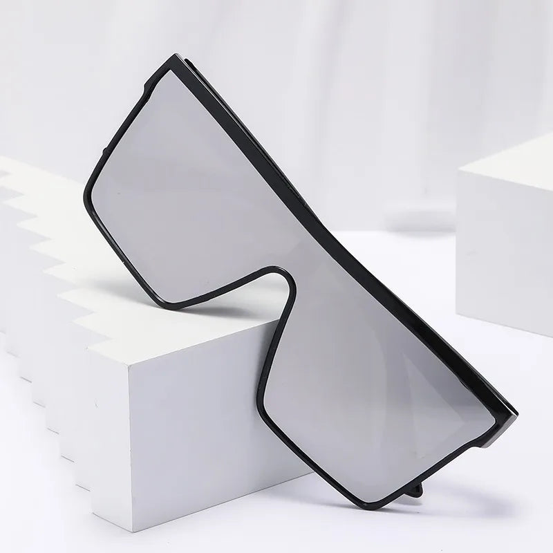 A pair of black-framed retro square sunglasses resting on a white block.