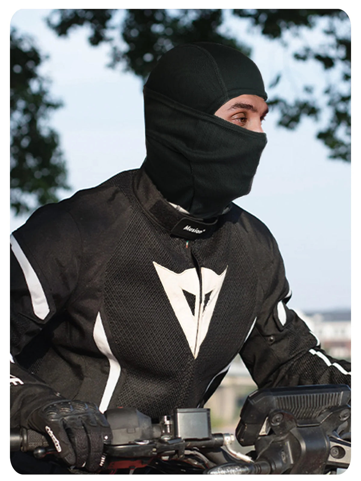 A man wearing a black mesh balaclava face mask while riding a motorcycle.