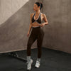 Eine Frau modelliert ein braunes Zwei-teiliges Sport-BH und Leggings-Set in einem Studio.