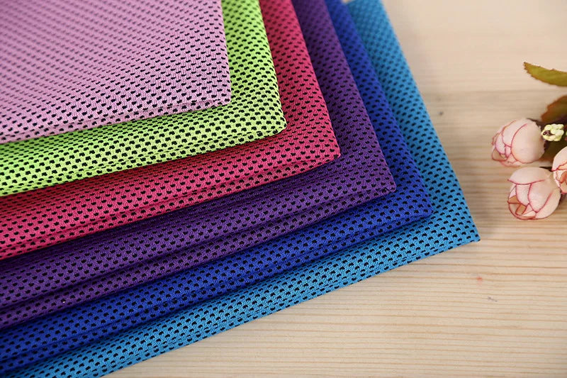 A stack of colorful microfiber cooling towels in various shades of purple, pink, green, and blue.
