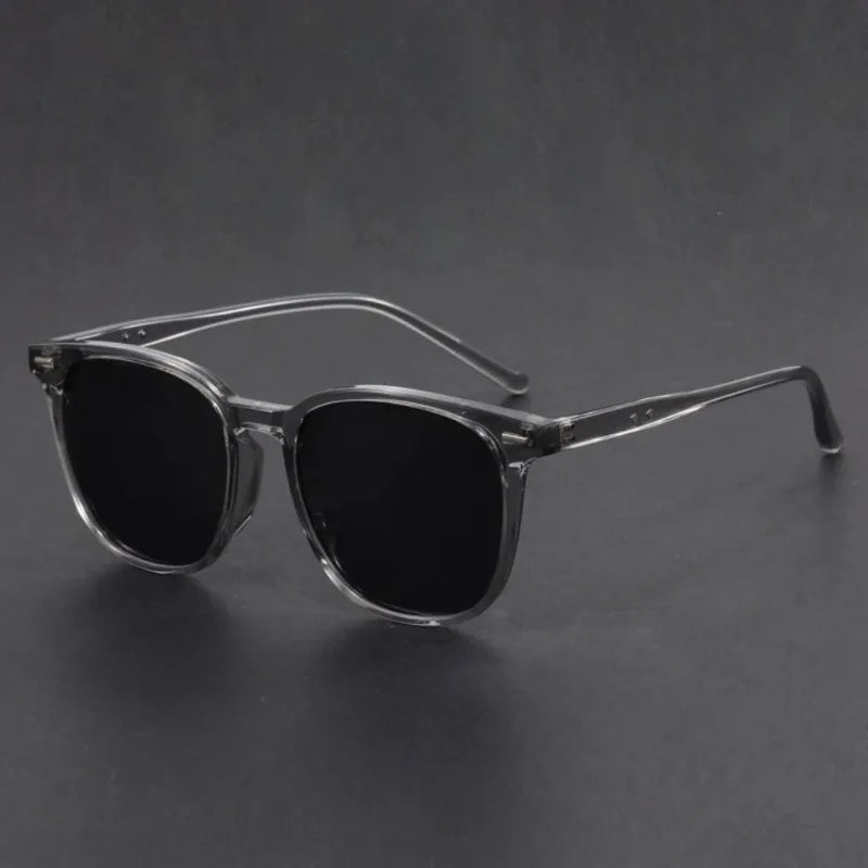 A pair of clear-framed, black sunglasses resting on a dark surface.