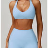 A woman models a light blue padded sport yoga bra and matching bottoms.