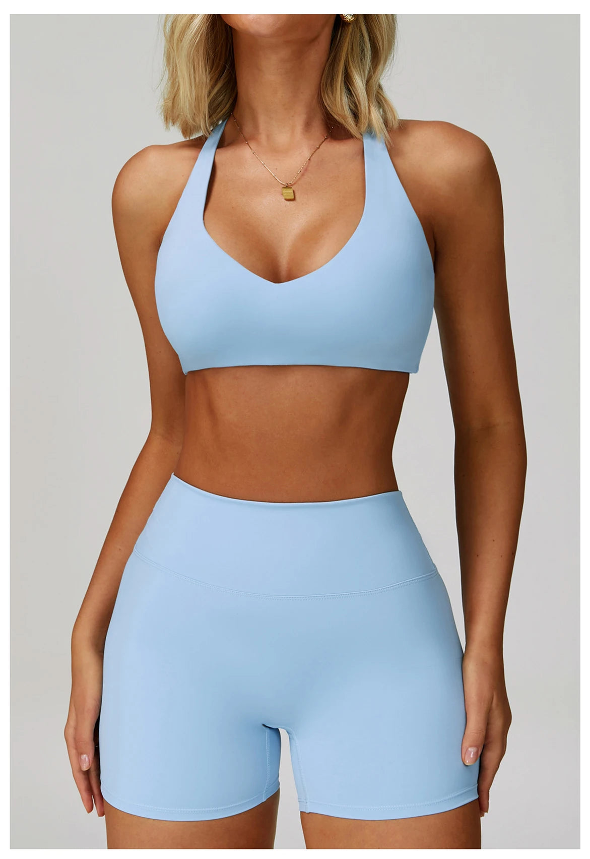A woman models a light blue padded sport yoga bra and matching bottoms.