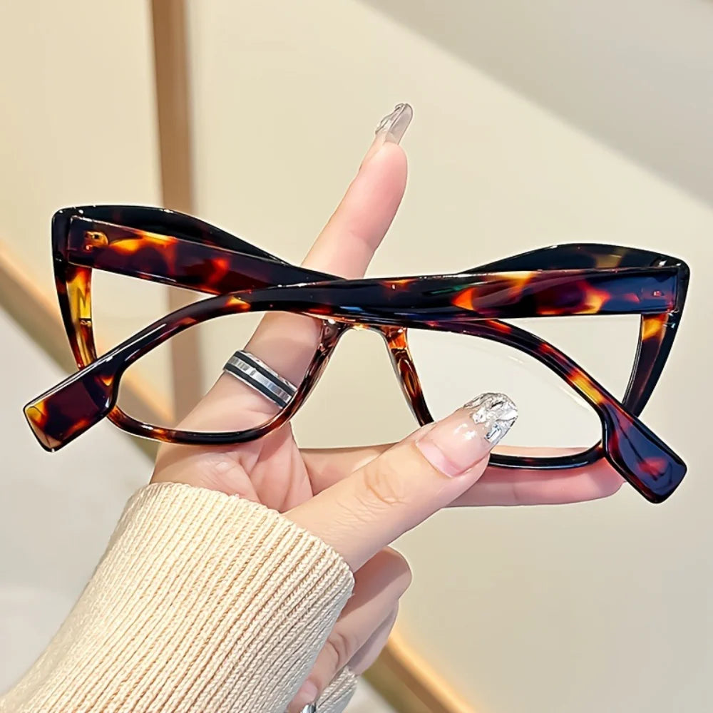 A hand holds a pair of vintage color block blue light blocking eyewear with dark brown and amber lenses.