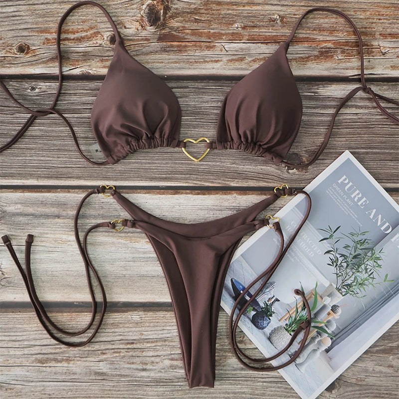 A brown solid color halter bikini set laid out on a wooden surface next to a magazine.