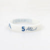 A white silicone wristband with blue text reading 5 and a signature.