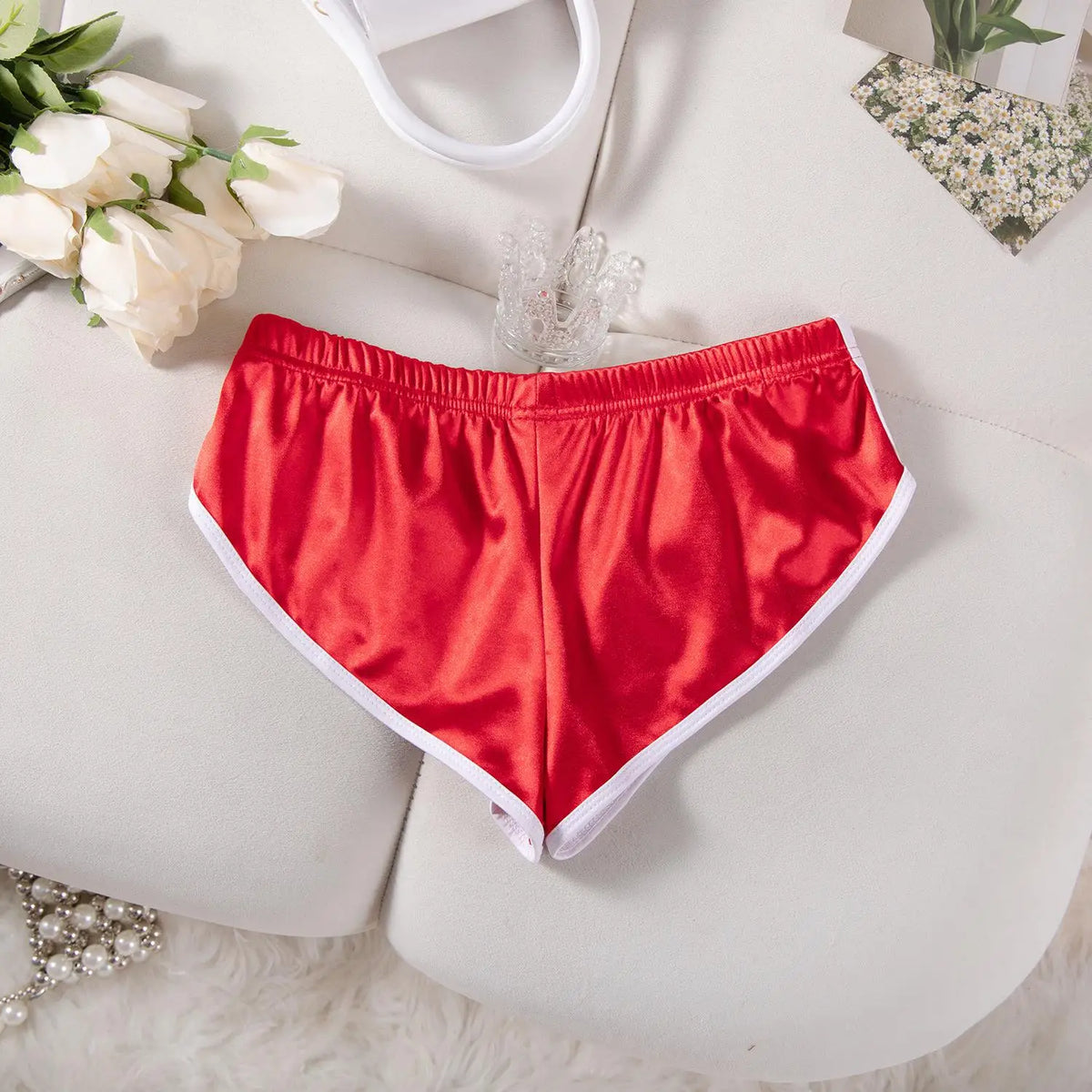Ein Paar leuchtend rote, elastische Laufshorts für Damen, flach auf einer weißen Oberfläche.