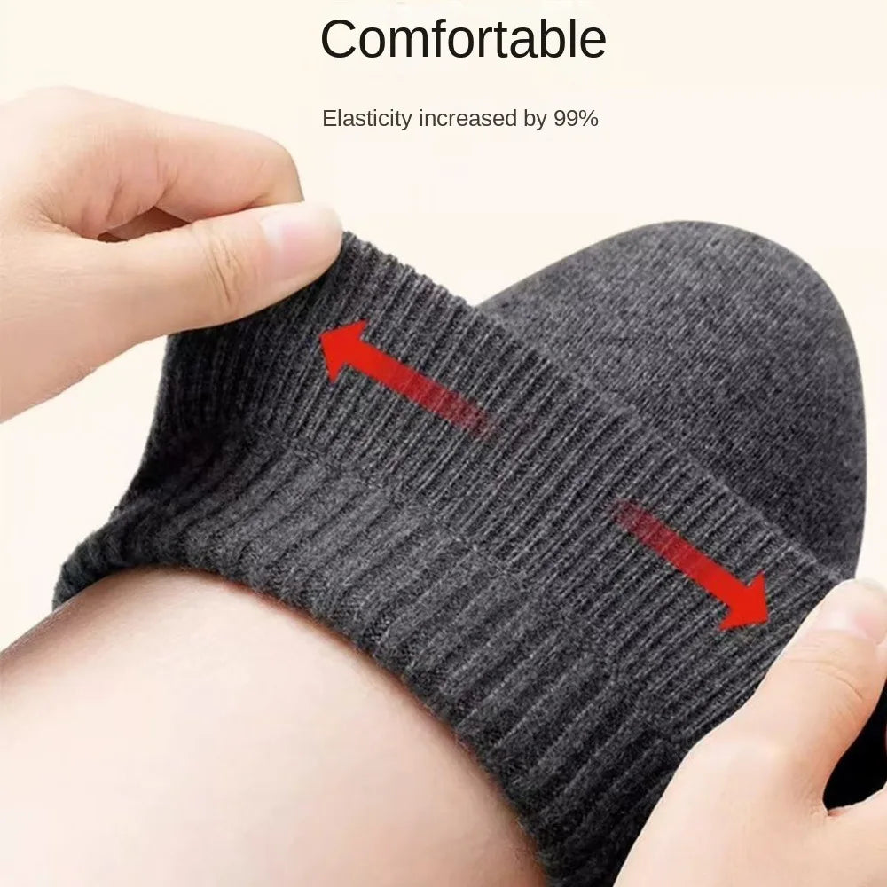 A hand is holding a dark gray knitted knee warmer, showing its elasticity.